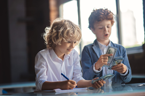 Calculations. Two boys counting money and making notes