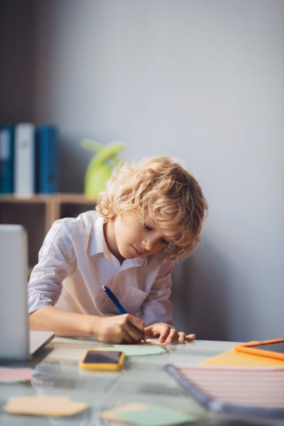 istock Cute blonde boy writing something and looking busy 1266100374