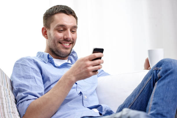 istock smiling man with smartphone at home 1266103060