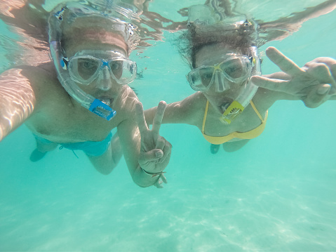 Snorkeling Young Caucasian couple with an action camera floating in the sea and making selfies.