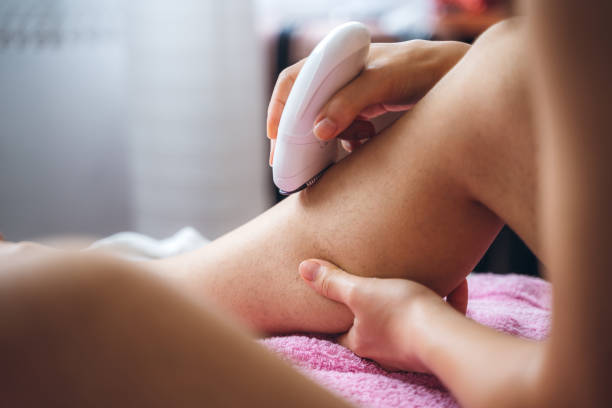 mujer afeitando las piernas con depilador - leg waxing fotografías e imágenes de stock