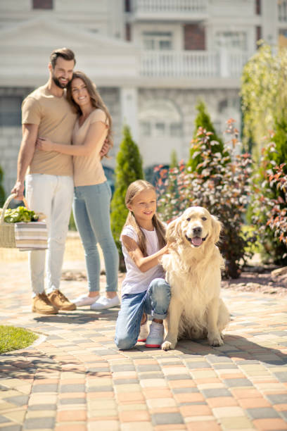 istock Cute girl stroking her pet while parents standing near 1266109868