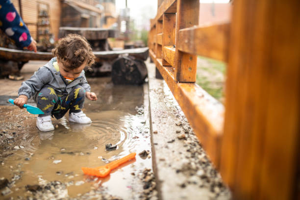 istock Little boy playing with water from puddle after rain, during autumn day 1266113973