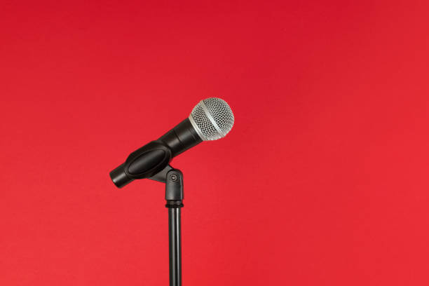 istock Microphone and stand, isolated against a bright red background 1266114173