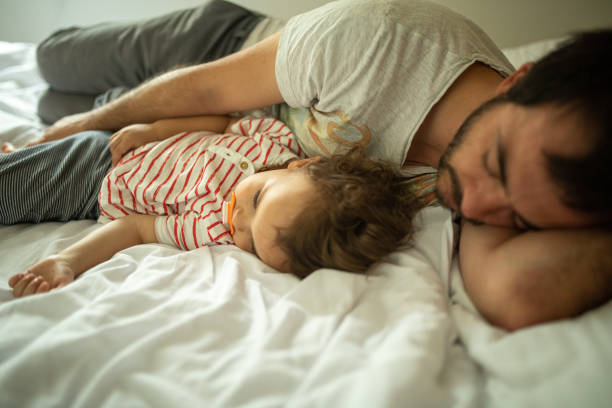 istock Son and father sleeping together on bed early in the morning 1266114191