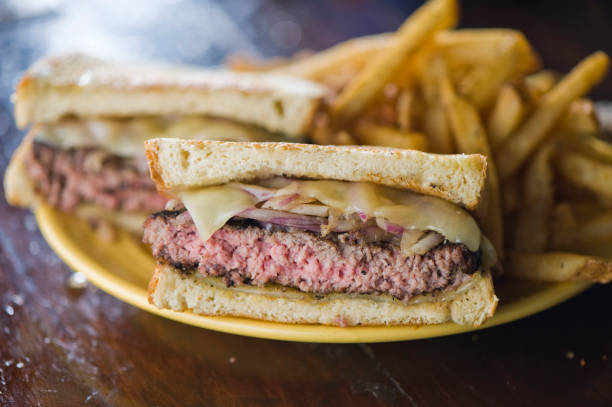 istock Bacon cheeseburger. Classic American style hamburger with all beef patties, crispy Bacon, melted Swiss & cheddar cheese, caramelized onions, lettuce, tomato, on a toasted brioche bun & served w/ crispy French fries. American Bar food favorite. 1266114307