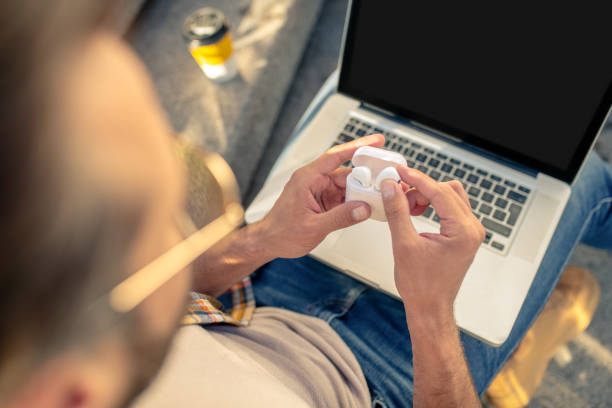 Man with open laptop and wireless headphones in case