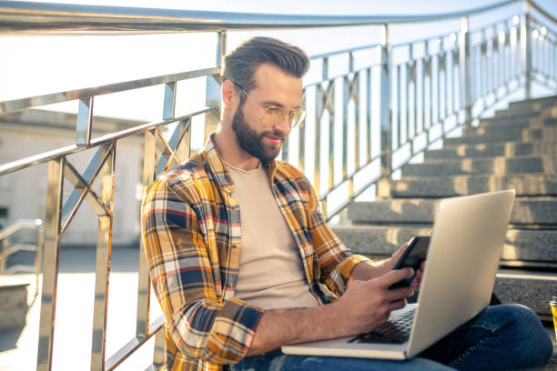 istock Man in glasses with smartphone on steps 1266119819