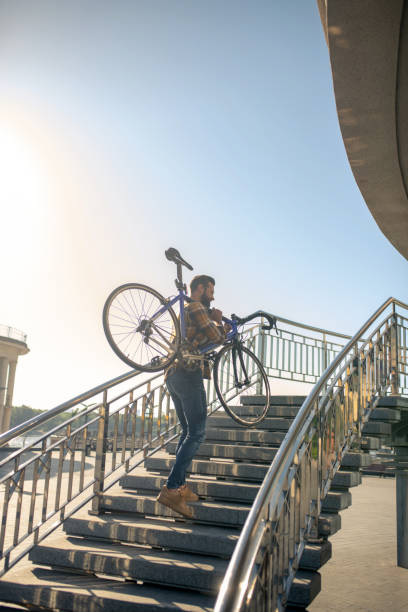 istock Young man carrying bicycle up the steps 1266119832