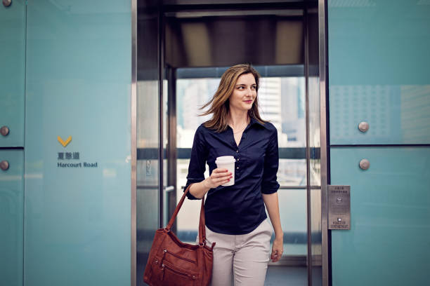 Young businesswoman is exiting elevator going to her office Young businesswoman is exiting elevator going to her office outdoor elevator stock pictures, royalty-free photos & images