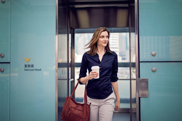 young businesswoman is exiting elevator going to her office - business business person ceo coffee imagens e fotografias de stock