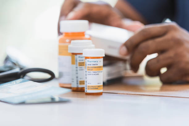 Unrecognizable male nurse or doctor reviews medications for patient A close up photo of an unrecognizable man, possibly a nurse or a doctor, reviewing medications for a patient. blood pressure medication stock pictures, royalty-free photos & images