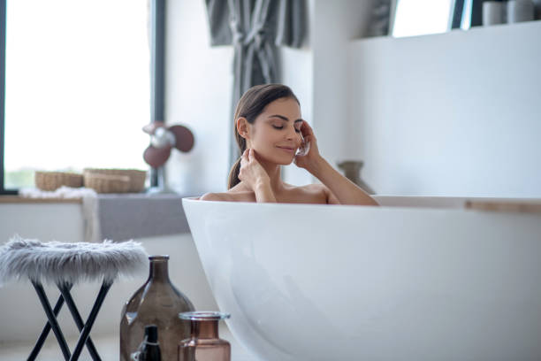 mujer teniendo un baño y mirando relajado - bathtub women bathroom relaxation fotografías e imágenes de stock