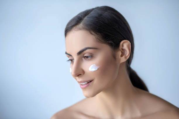 istock Cute woman with cream on her cheeks looking peaceful 1266123620