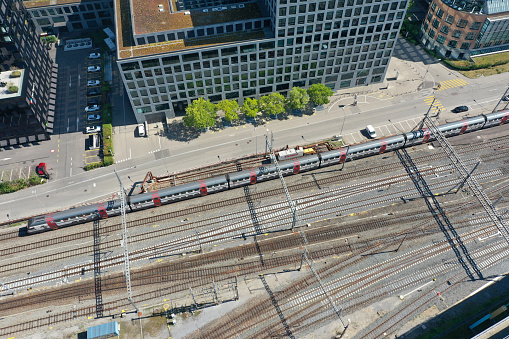Zurich Altstetten close-up image with railroad tracks and an intercity train passing. The high angle image was captured during summer season.