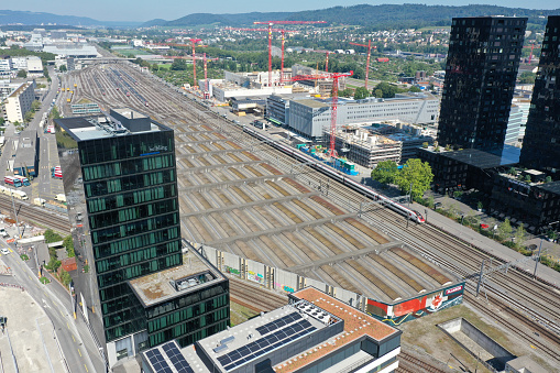 Zürich Altstetten with an office building in the foreground and the railroad tracks in the background. The wide angle image was captured during summer season.