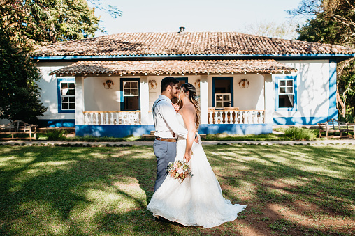 profile of newlyweds on the background of wall, barrels and tree.