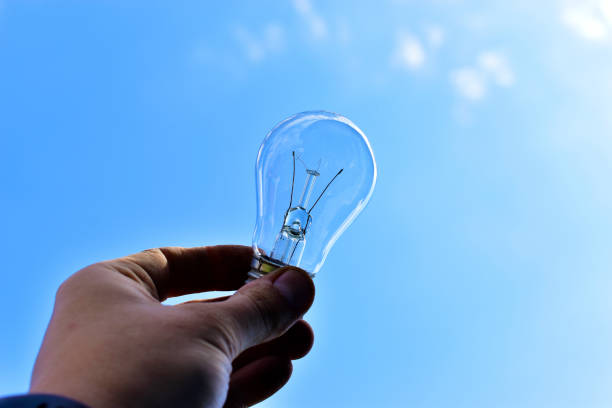 istock Glittering incandescent lamps in hand on a blue background 1266133698