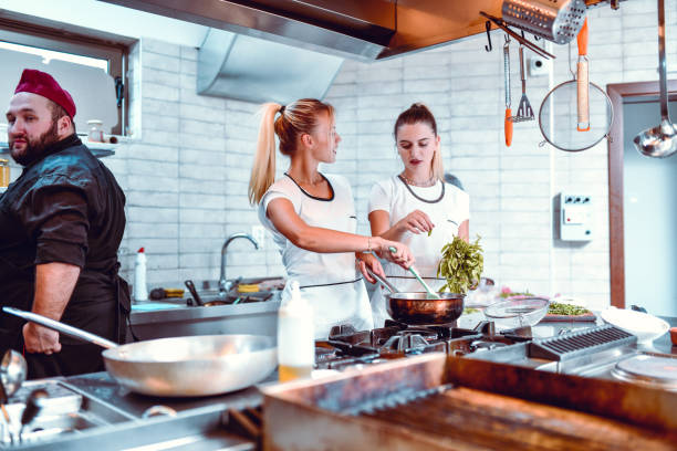 istock Females Helping Chef In Restaurant Kitchen 1266136580