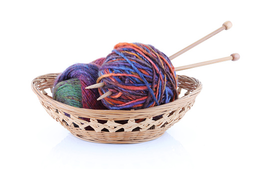 A basket with two balls of wool and knitting needles