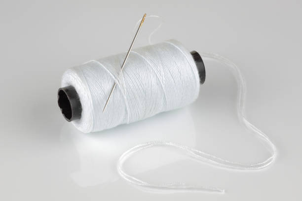 A white cotton reel and needle with reflection