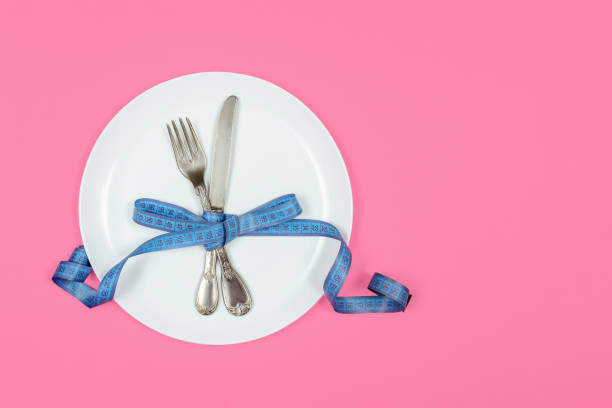 istock Measuring tape on a fork and knife - dieting concept 1266137781