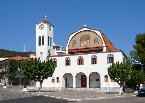 Marmari, Evia island, Greece. August 2020:  St. George's Church with a chapel and bell tower on the waterfront of the resort town of Marmari on the Greek island of Evia in Greece on a summer day