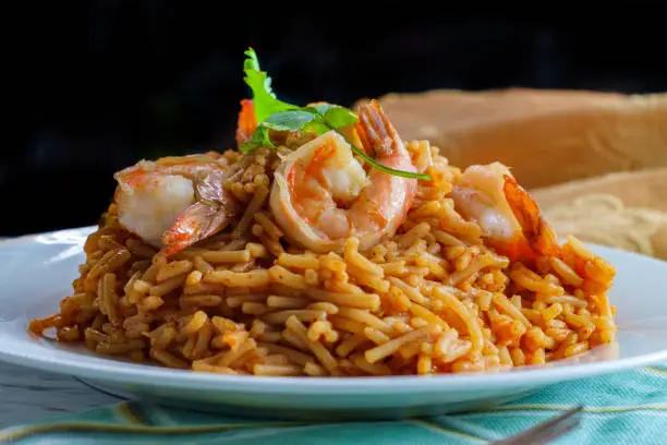 Tail-on shrimp Spanish rice with vermicelli pasta on marble kitchen table