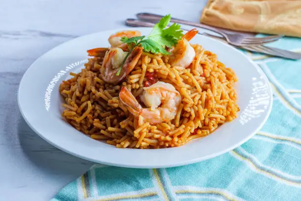 Tail-on shrimp Spanish rice with vermicelli pasta on marble kitchen table
