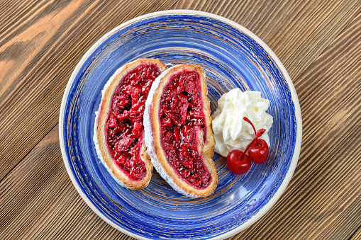 Slices of cherry strudel with whipped cream