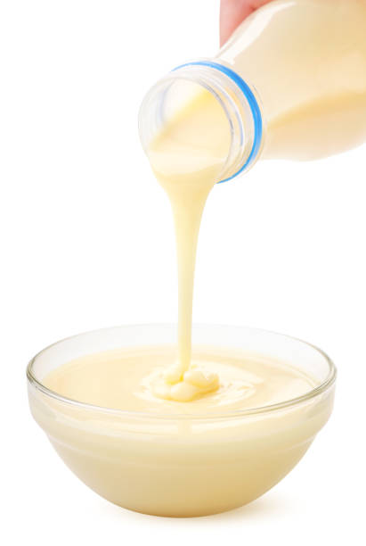 istock Condensed milk from the package is poured into a plate on a white background. Isolated 1266146966
