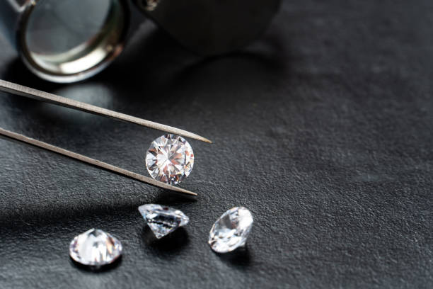 istock brilliant cut diamond held by tweezers on black background 1266149071
