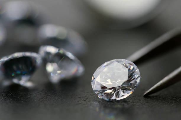 istock brilliant cut diamond held by tweezers on black background 1266149276