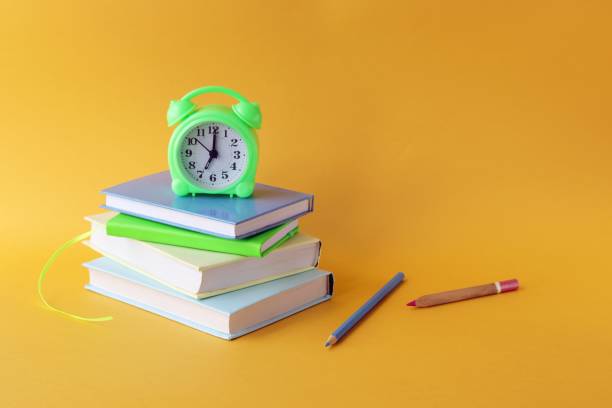 istock Back to school, stationery, alarm clock, stack of books on bright background 1266149418