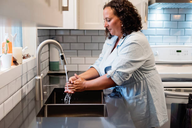 istock Mature woman washing hands in kitchen sink. 1266156824