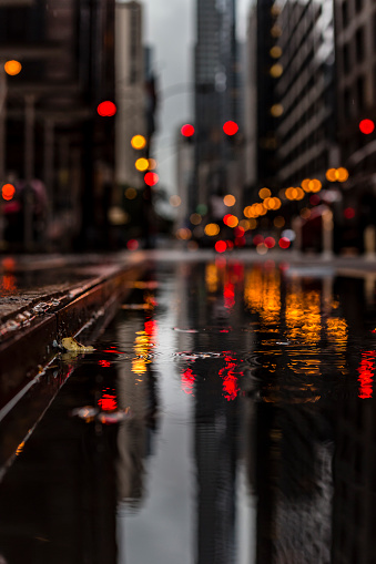 raindrops and selective focus with a reflection on a city street surrounded by skyscrapers