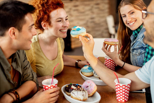 istock Group of cheerful friends sharing donuts in a cafe. 1266159948