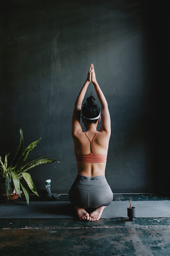 Namaste: a fit woman in sportswear practicing yoga at home.