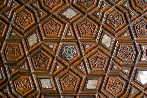 Detailed close up of an intricately carved wooden panel featuring traditional Islamic geometric star and polygon motifs, showcasing historic craftsmanship, symmetrical design and rich brown tones often found in Ottoman and Middle Eastern architectural interiors, decorative doors, ceilings and heritage monuments