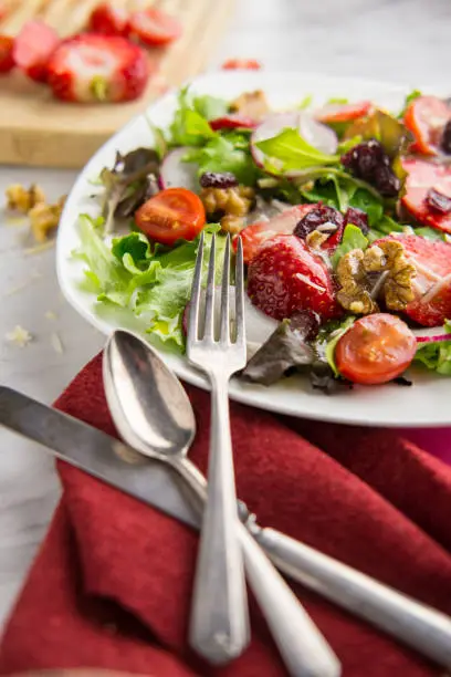 Fresh organic romaine lettuce salad with walnuts radishes and strawberries