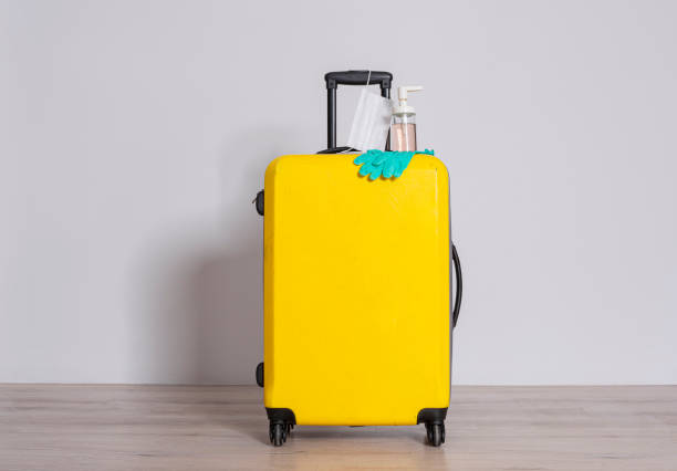 istock Suitcase with protective face mask, hand sanitizer and protective gloves over gray background 1266163812