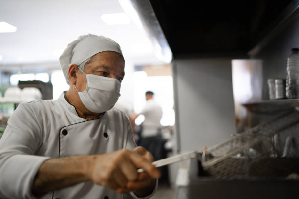 istock Chef working in a commercial kitchen, preparing deep-fried food 1266164138