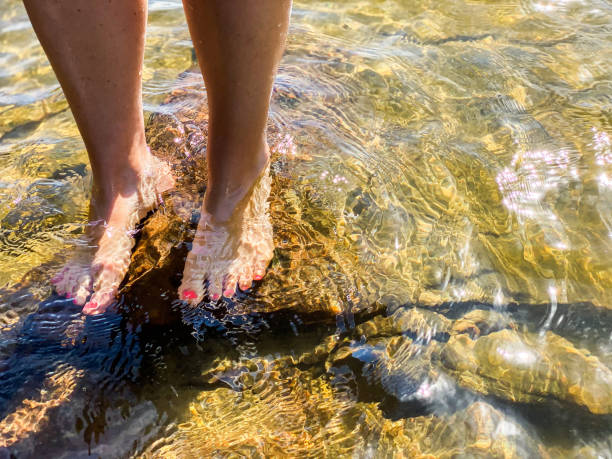 jovens pés em pé sobre rochas na água. - sweden summer swimming lake - fotografias e filmes do acervo