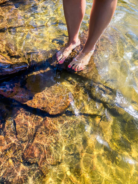 jovem mulher em pé sobre rochas na água. - sweden summer swimming lake - fotografias e filmes do acervo