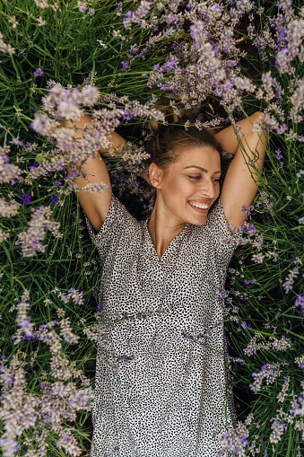 Photo of a smiling young woman lying in lavender; enjoying the beautiful and peaceful weekend getaway, far from the hustle of the city.
