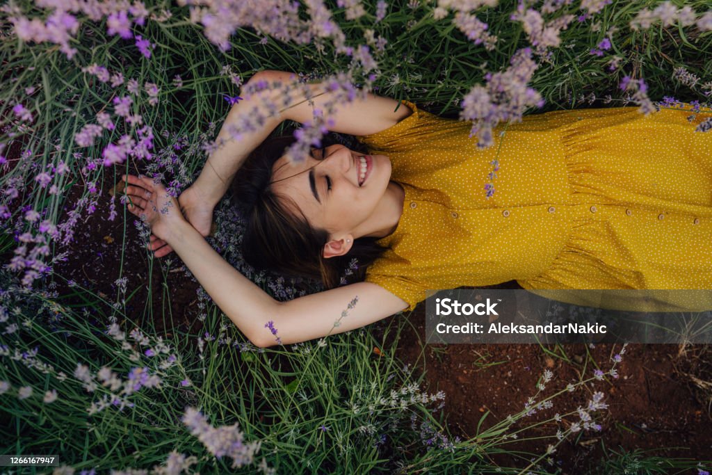 Into the loving arms of nature Photo of a smiling young woman lying in lavender; enjoying the beautiful and peaceful weekend getaway, far from the hustle of the city. Women Stock Photo