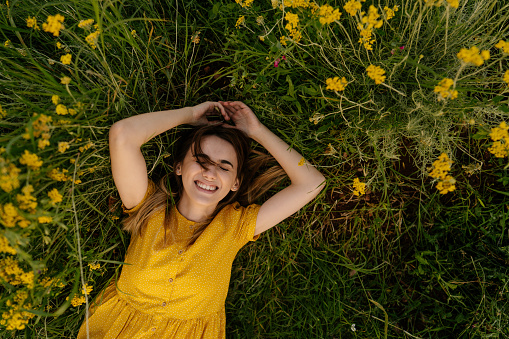 Photo of a smiling young woman lying in immortelle; enjoying the beautiful and peaceful weekend getaway, far from the hustle of the city.
