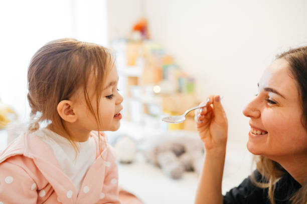Mother giving medicine to little girl Sick girl taking a medicine from a spoon. Mother is taking care about her little girl child liquid medicine stock pictures, royalty-free photos & images