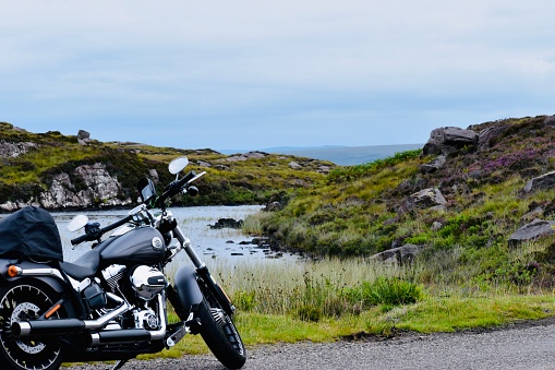 Scotland / United Kingdom - August 02, 2020: Small pond of water surrounded by green grass and a grey motorbike in front of it