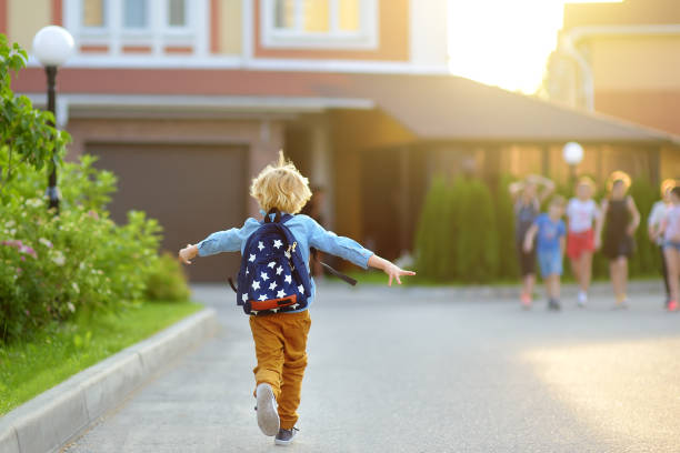 petit écolier joyeusement courant à l’école après vacances. rencontre d’enfant avec des amis. l’éducation des enfants. concept de retour à l’école. - cartable photos et images de collection